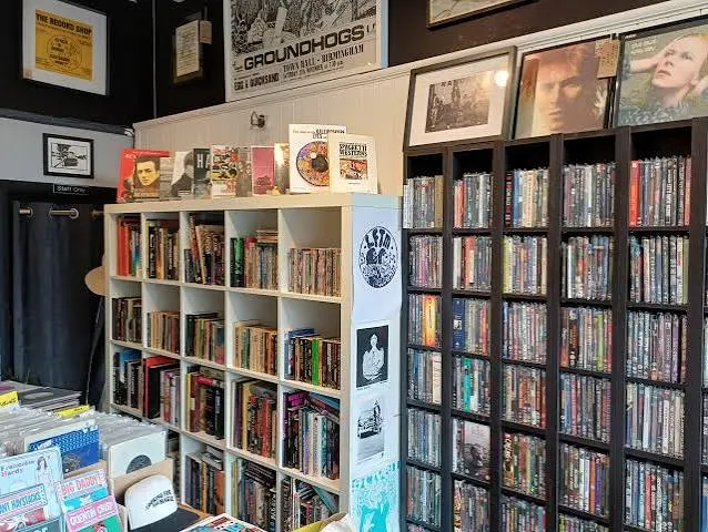 Shelves of music books and framed prints beside racks of records inside the shop.