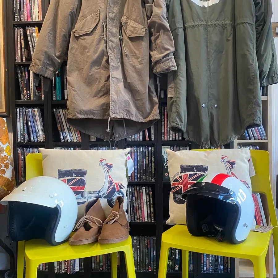 A rail of vintage jackets beside a shelf of helmets and the racks.